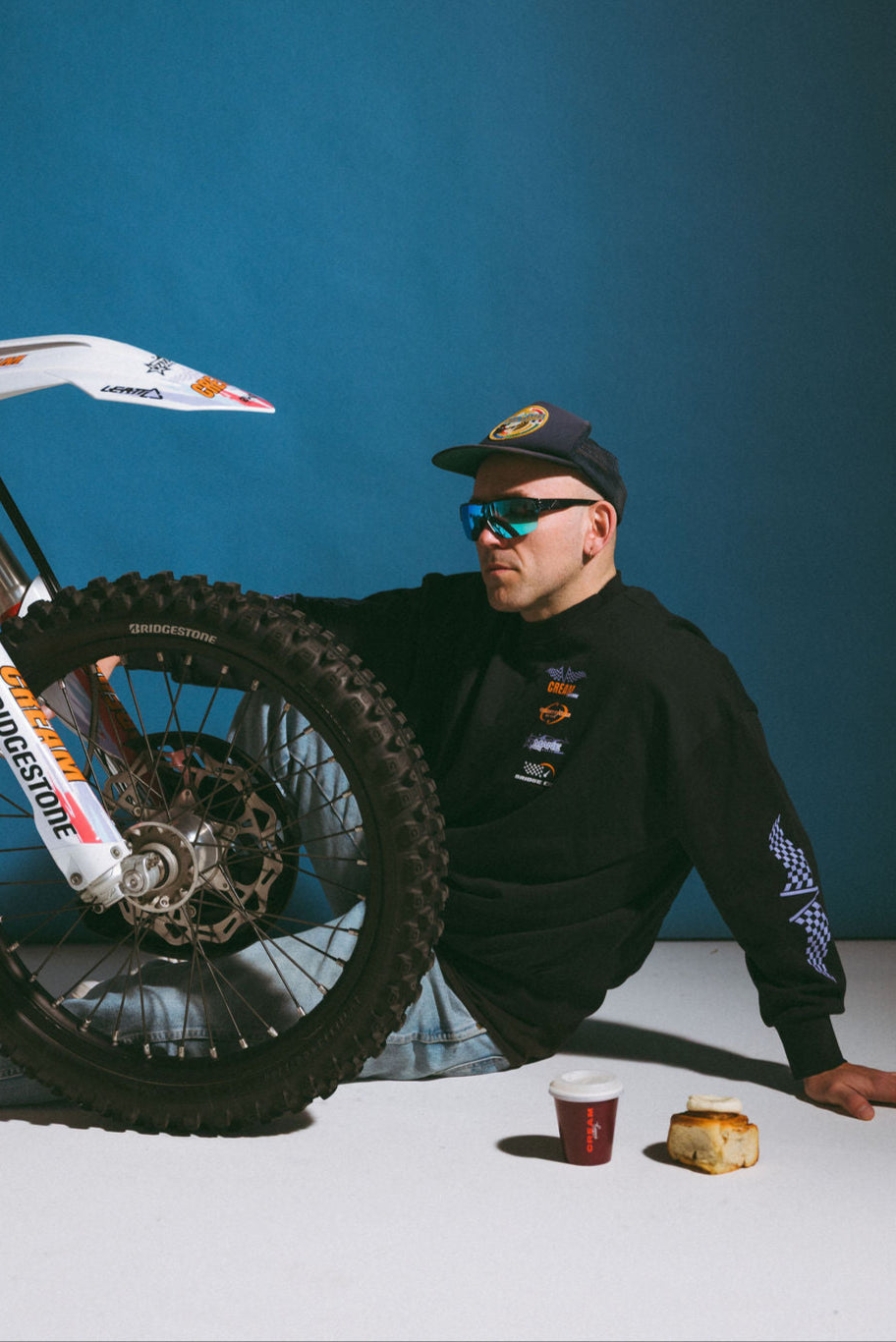 Man leaning against a dirt bike with a blue background